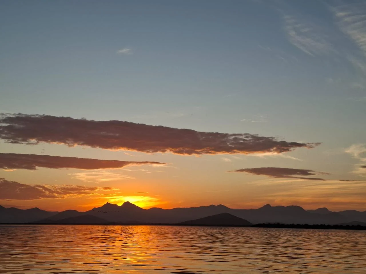 Sol se pondo atrás das montanhas e refletindo na água