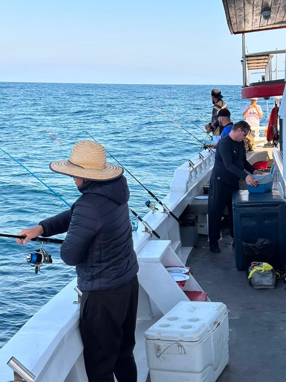 Pescador com a linha na água junto à lateral do barco