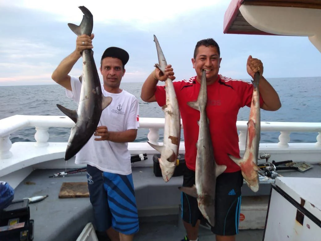 Dois pescadores exibem as capturas a bordo